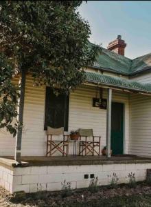 un porche de una casa con 2 sillas y una mesa en Primrose Cottage, en Mandurama