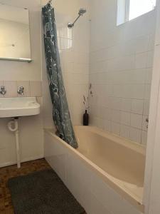 un baño con bañera y lavabo en Primrose Cottage, en Mandurama