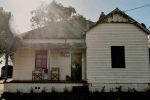 Una vieja casa blanca con un porche con dos sillas. en Primrose Cottage, en Mandurama 29 fotos más