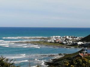 a view of a beach with houses and the ocean at Petite Selfcatering Accommodation Struisbaai SA in Struisbaai