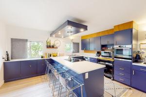 una cocina con armarios azules y encimeras blancas en Riverfront Escape, en Monte Rio
