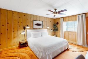 1 dormitorio con cama blanca y ventilador de techo en Riverfront Escape, en Monte Rio