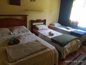 a bedroom with three beds and a window at O Brejo Encantado Hospedagem e Pousada in Embu