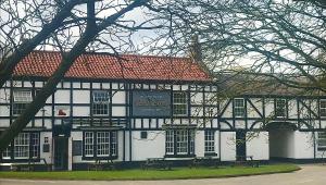 um edifício branco e preto com bancos em frente em Red Lion Coaching Inn em Redbourne