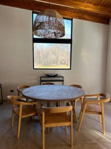 ein Esszimmer mit einem Tisch, Stühlen und einem Fenster in der Unterkunft Casa de la Libélula con pileta in Alta Gracia