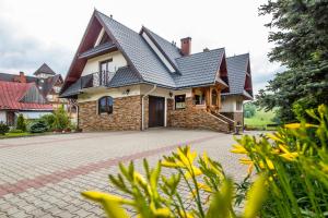 a house with a tile roof and a driveway at Folkowy Dworek SPA & Fun in Murzasichle
