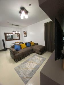 a living room with a brown couch and yellow pillows at CDO UPTOWN CONDOMINIUM in Cagayan de Oro