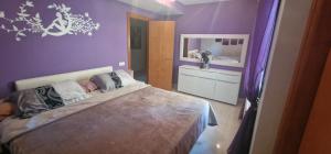 ein lila Schlafzimmer mit einem Bett und einem Spiegel in der Unterkunft CASA RODA DE BARÁ in Roda de Berà