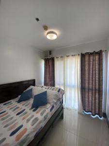 um quarto com uma cama com almofadas e cortinas azuis em CDO UPTOWN CONDOMINIUM em Cagayan de Oro