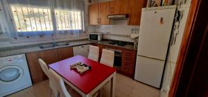 eine Küche mit einem roten Tisch und einem weißen Kühlschrank in der Unterkunft CASA RODA DE BARÁ in Roda de Berà