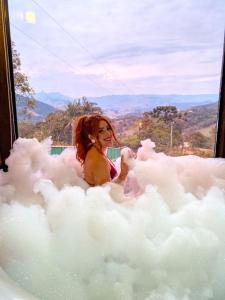 a woman is sitting in a cloud bathtub at Chalé Luar da Mantiqueira in Sapucaí-Mirim