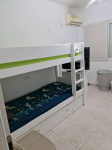 a white bunk bed in a room with a chair at Lovely Apt Close to Beach in Nahariyya