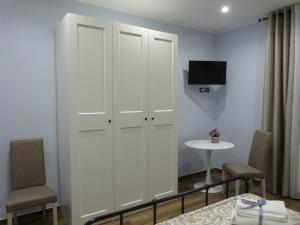 1 dormitorio con armarios blancos, mesa y TV en HOME SWEET HOME, en Sammichele di Bari
