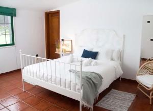 a white bedroom with a white bed and a chair at La Macadamia in Las Lagunas