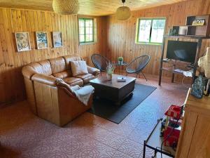 sala de estar con sofá de cuero y TV en La Macadamia, en La Laguna