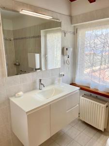 La salle de bains blanche est pourvue d'un lavabo et d'un miroir. dans l'établissement Villa Carrera, à Malcesine