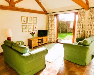 a living room with two green couches and a television at Smallthorns Barn in Market Harborough