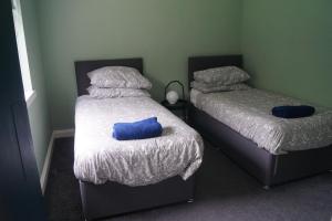 two beds in a room with two blue pillows on them at Cunninghame 3 in Beith
