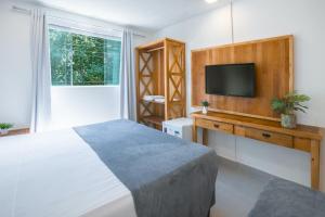 a bedroom with a bed and a flat screen tv at Hotel Cajueiro Guarujá in Guarujá