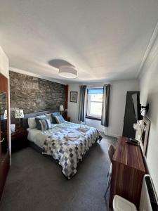 ein Schlafzimmer mit einem Bett und einer Steinmauer in der Unterkunft Islay Frigate Hotel in Tarbert