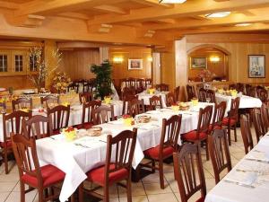 une salle à manger avec de longues tables, des chaises et un tissu de table blanc dans l'établissement Sport Hotel Pampeago, à Tesero
