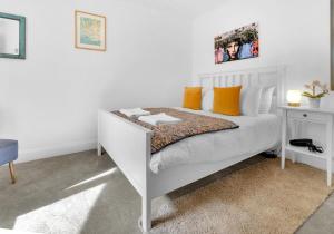 a bedroom with a white bed with orange pillows at Golden Sunset House with free parking by My Getaways in Brighton & Hove