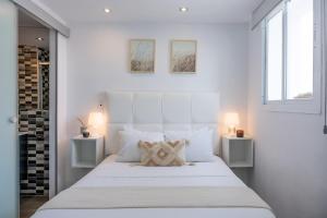 a white bedroom with a large white bed with two lamps at Casa Hibiscus Marbella in Marbella