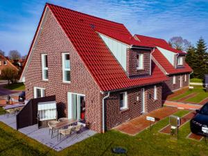 a red roofed house with a red roof at Küsten Apartments Tannenhausen in Aurich