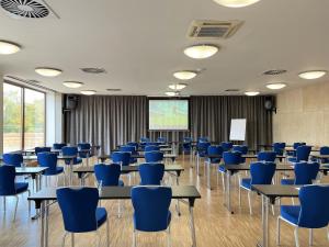 a classroom with blue chairs and tables and a screen at Blue Orange Resort in Prague