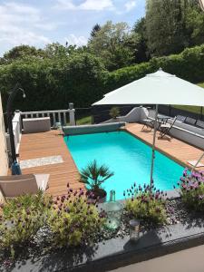 a swimming pool with an umbrella and a wooden deck at Atelier des Rêves in Vichy