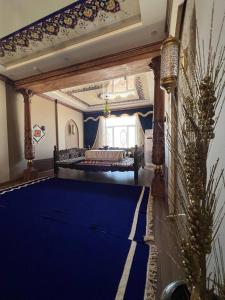 a large room with a blue carpet and a bed at Jannat Minor Boutique Hotel in Urganch