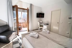 a bedroom with a bed and a desk and a window at Hotel Saligari in Verceia