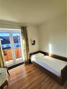ein Schlafzimmer mit einem Bett und einem großen Fenster in der Unterkunft Pension Schwartzwirt in Neusiedl am Steinfelde