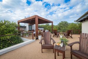 a patio with wooden chairs and a gazebo at Gem In The Bush Lodge in Hoedspruit
