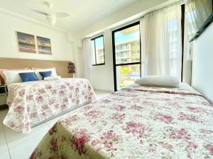 two beds in a room with windows at Mana Beach Muro Alto-Flat 12 Ohana e 20 Aloha Térreo Frente Piscina in Porto De Galinhas