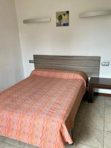 a bed in a room with a wooden headboard and a table at Hostal - Restaurante Asador Esperanza in Huesca