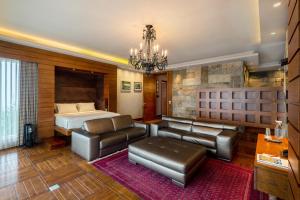 a bedroom with a bed and a couch and a chandelier at amã Stays & Trails Kailash House in Kodaikānāl