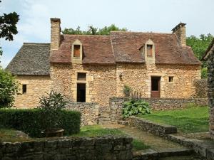 stary kamienny dom z kamienną ścianą w obiekcie Chambre d'Hôtes La Rossillonie w mieście Beynac-et-Cazenac
