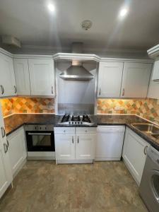 cocina con armarios blancos y fogones en Burlington Mansions, en Bournemouth