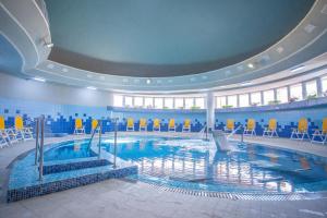 a large swimming pool in a building with chairs at Hotel International in Baile Felix