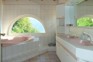 ein Badezimmer mit zwei Waschbecken und einem Bogenfenster in der Unterkunft Villa Nora in Faulensee