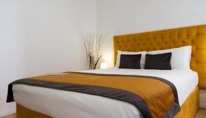 a bedroom with a large bed with a yellow headboard at Michelangelo Vatican Rooms in Rome