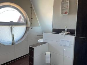 a bathroom with white cabinets and a round window at Villa Ostseewelle in Dranske