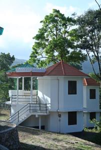 a white building with a porch and a tree at Jungle Villa Munnar in Pooppara