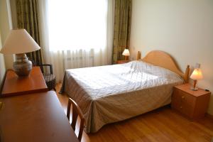 Premium Apartments Baku في باكو: غرفة نوم بسرير وطاولة مع مصباح