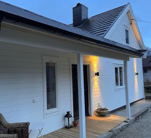 un porche de una casa blanca con terraza de madera en Cozy house in Eidfjord en Eidfjord