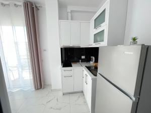 a white kitchen with white cabinets and a refrigerator at Villa Denis Ksamil in Ksamil