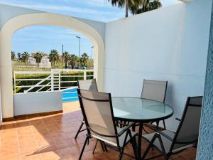 a patio with a glass table and chairs on a balcony at Caseta Rabdells Olivanova 150m de la playa in Oliva