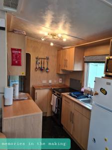 a kitchen with wooden cabinets and a white refrigerator at Memories in the making in Paignton