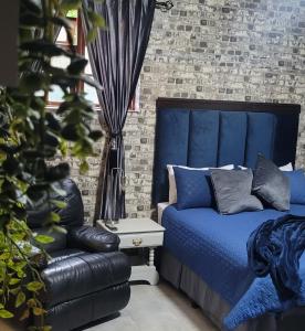 a bedroom with a blue bed and a chair at Pandora's Guest Lodge in Klerksdorp